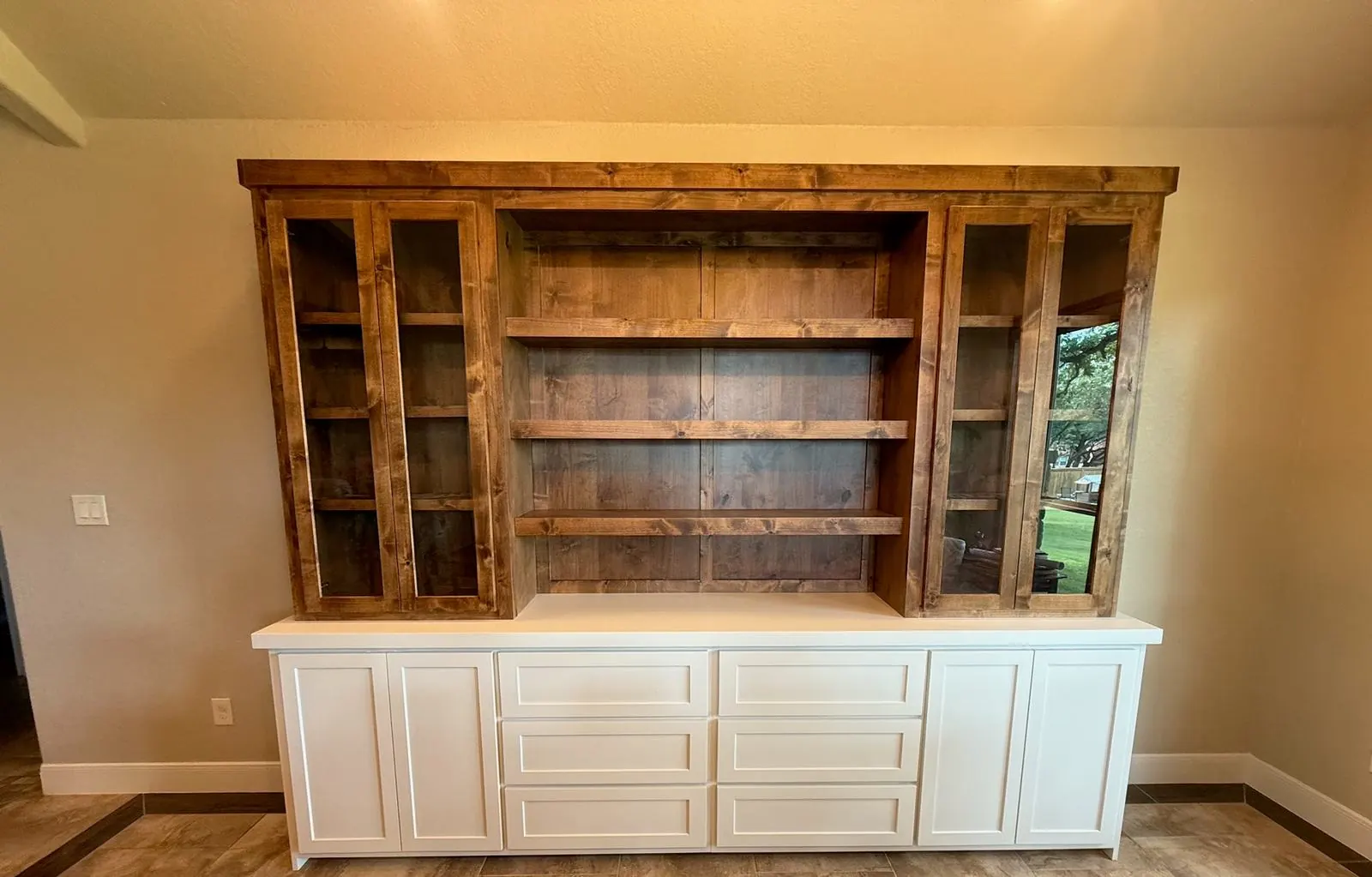 Knotty alder hutch with glass doors and open shelves on a white painted base of doors and drawers