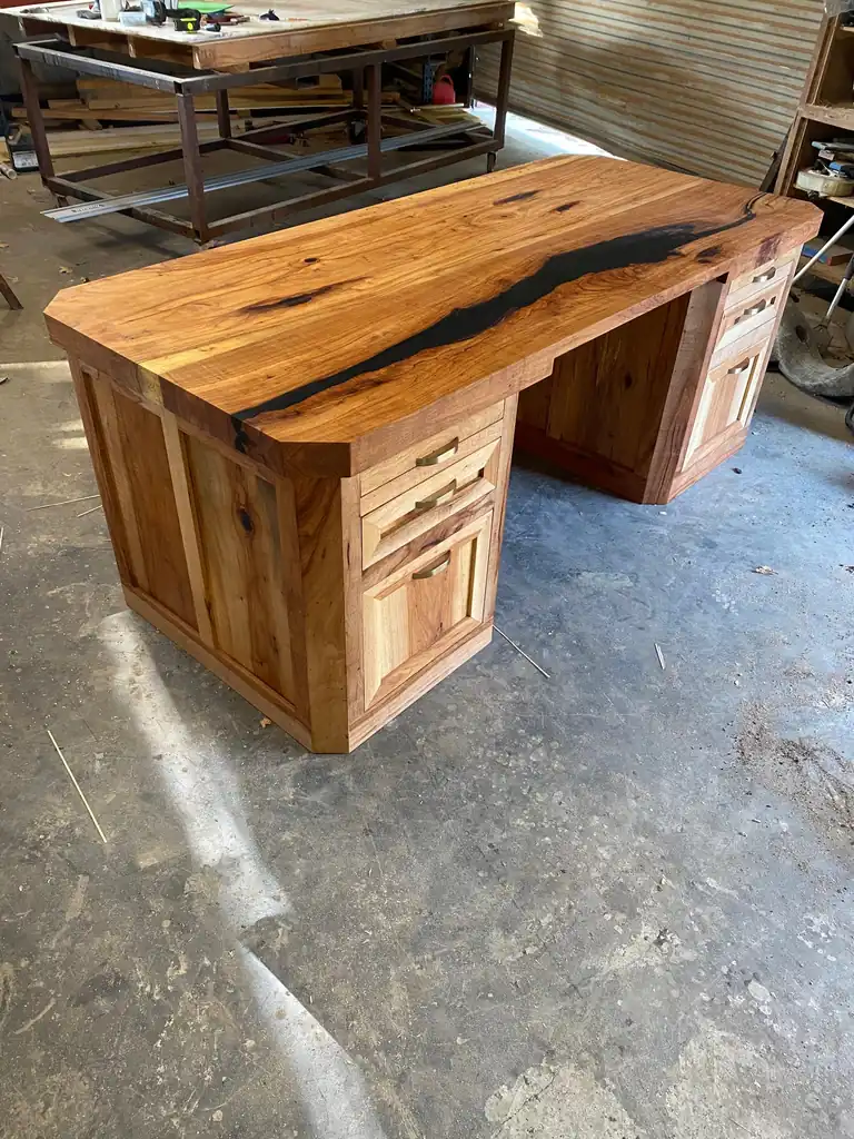 Live-edge hickory desk with a black resin river top and two drawer pedestals, in the shop