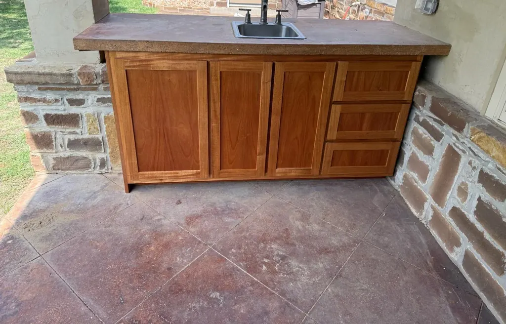 Patio cabinet with shaker doors and three drawers under a poured concrete top with a bar sink