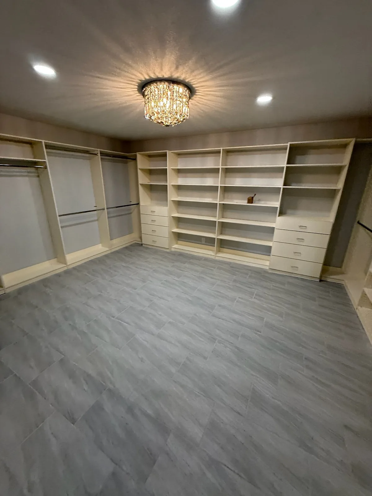 Walk-in closet with built-in shelving, drawer banks and hanging sections under a crystal light