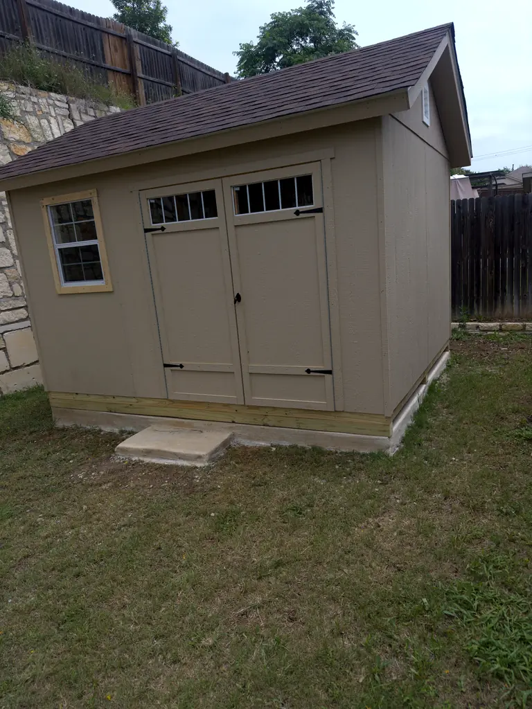 Finished taupe gable storage shed with double carriage doors, window and raised base