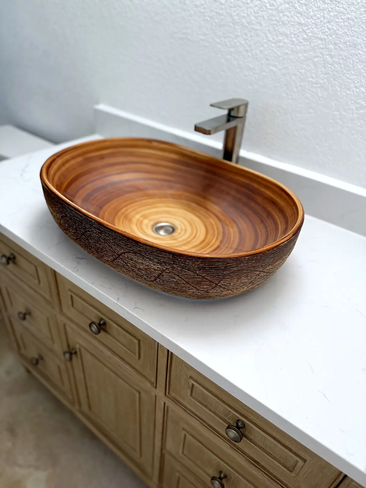 Wood-grain vessel sink with brushed faucet on white quartz vanity